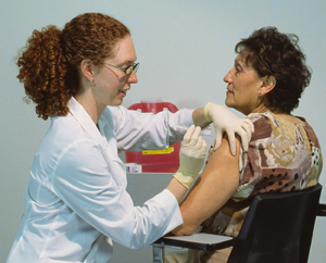 Healthcare provider preparing to give injection in woman's upper arm.